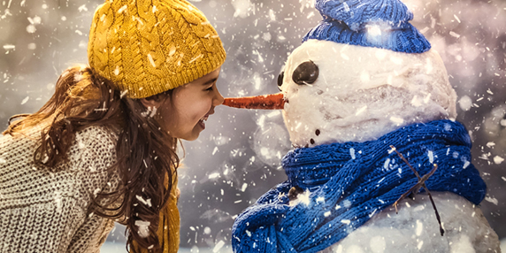 En flicka hälsar på en snögubbe i ett vintrigt landskap