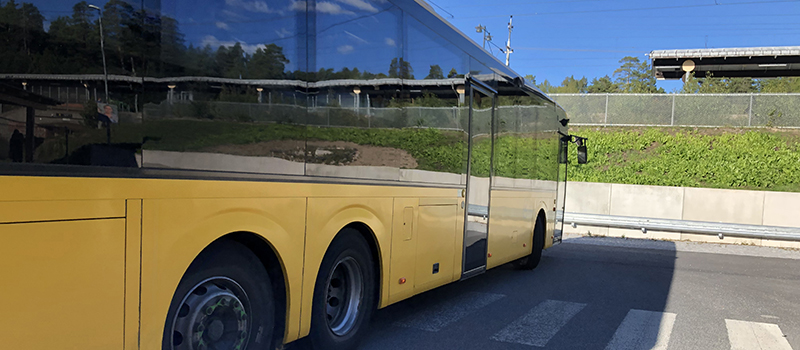 Gul buss med spegling av stationsområdet i Bålsta