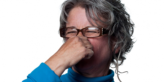 En kvinna håller för näsan för att det luktar illa.