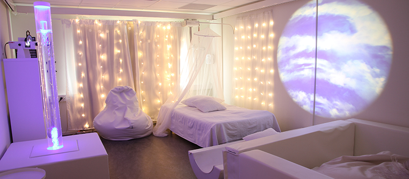 Bild på rum med dämpad belysning, bubbelrör, vattensäng, sacco-säck och projektor.