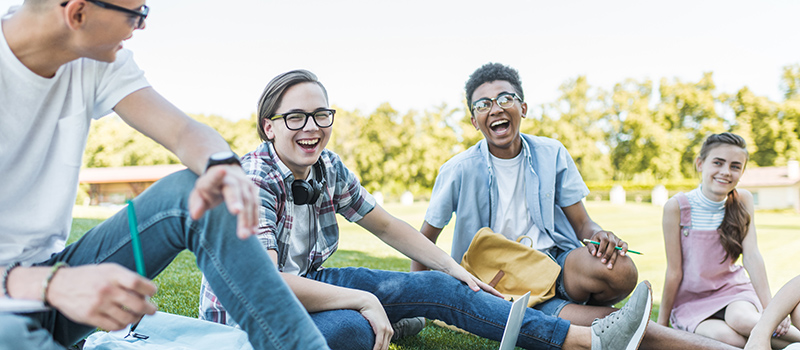 4 glada ungdomar som sitter på en gräsmatta 