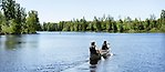 På väg bort paddlar två personer i en sjö.