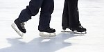 Benen på två skridskoåkare på en is